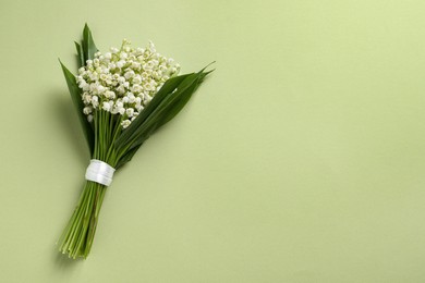 Photo of Beautiful lily of the valley bouquet on light green background, top view. Space for text