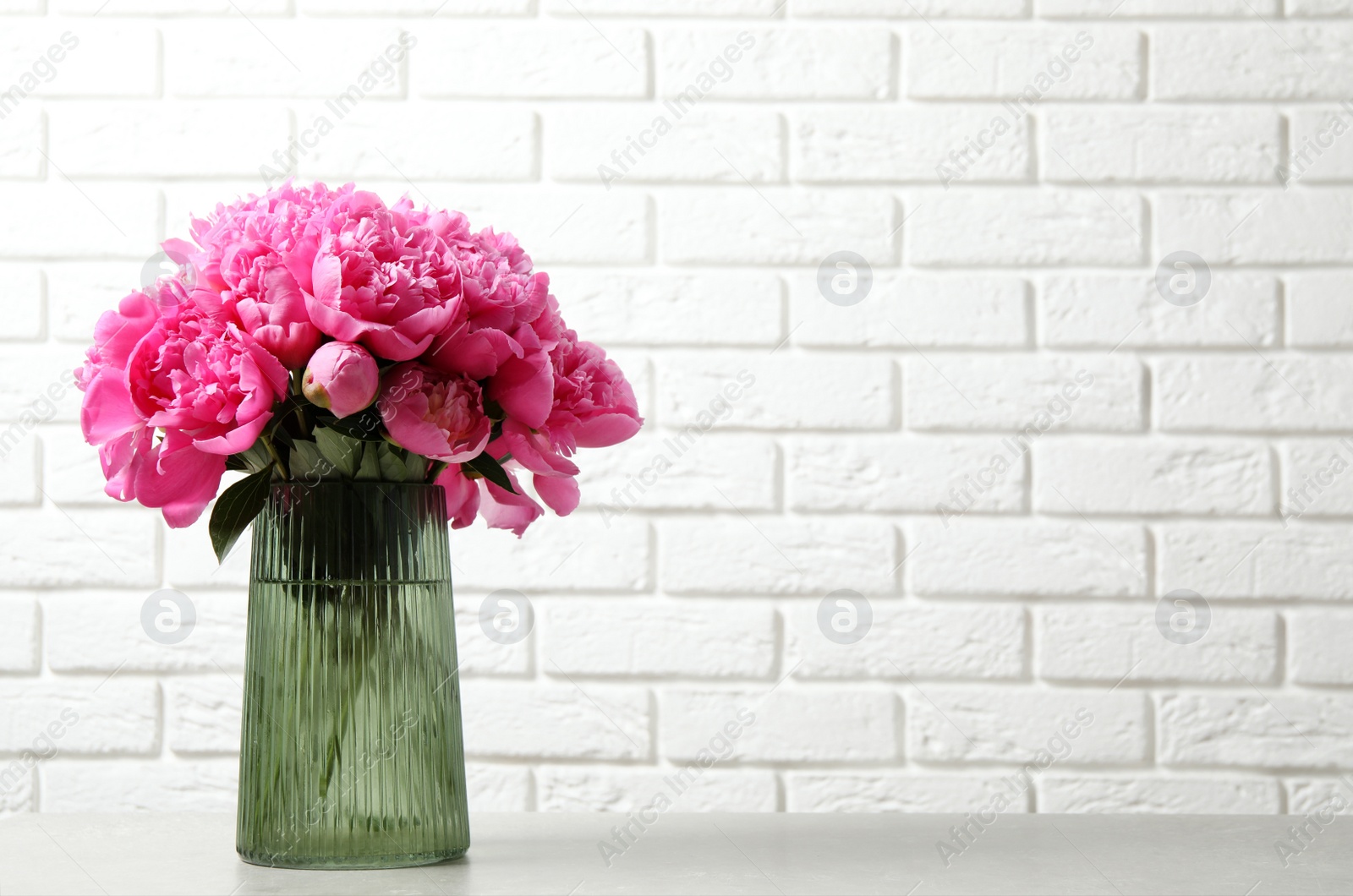 Photo of Bouquet of beautiful peonies in vase on table. Space for text