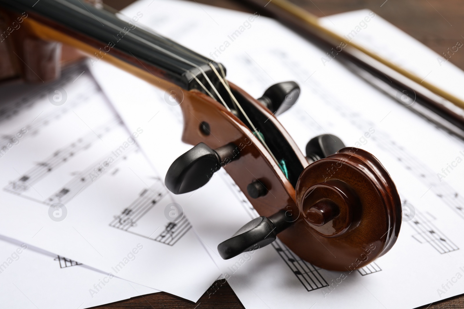 Photo of Beautiful violin and note sheets on table, closeup