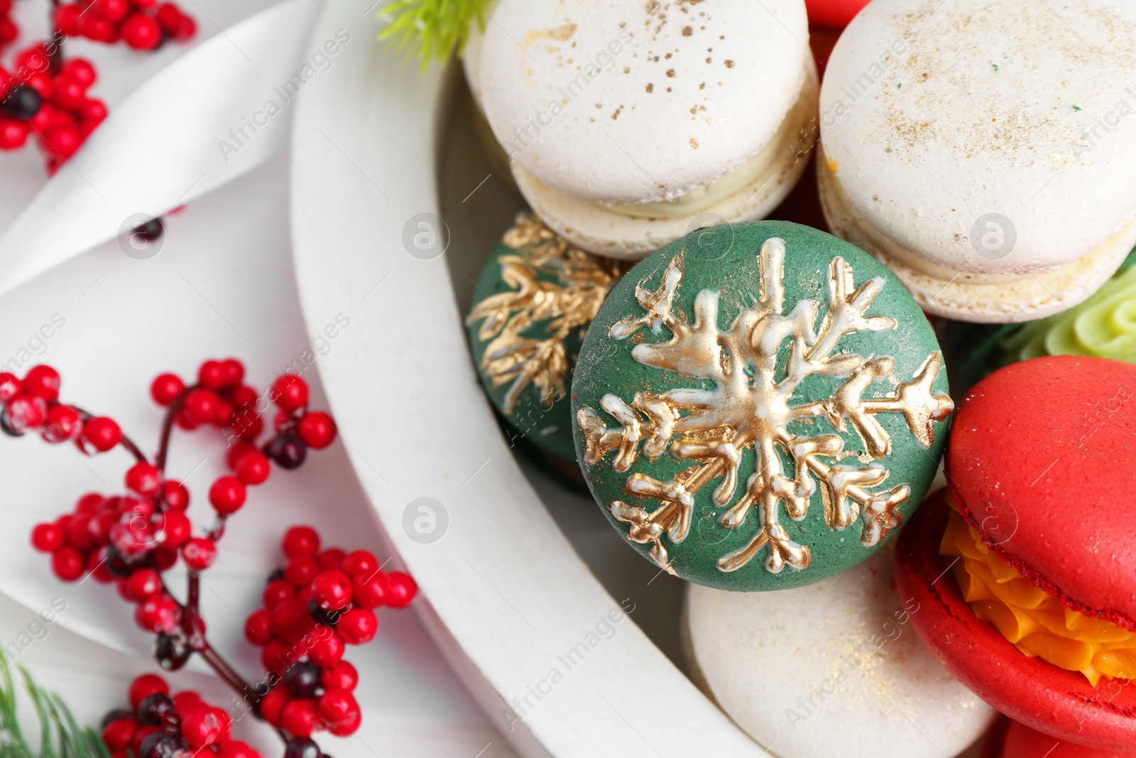 Photo of Different decorated Christmas macarons and festive decor on white table