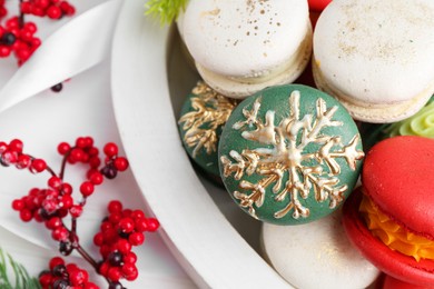 Different decorated Christmas macarons and festive decor on white table