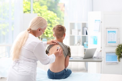 Doctor examining coughing little boy at clinic