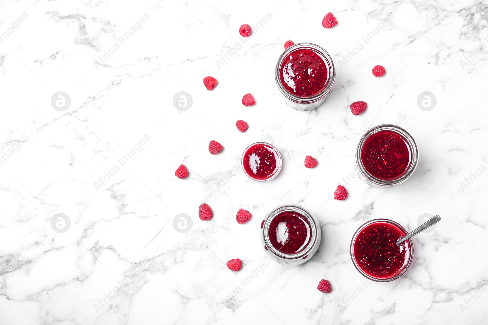 Photo of Beautiful composition with delicious raspberry jam on marble table, top view