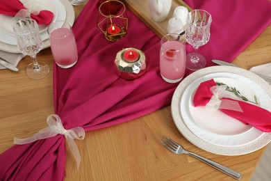 Photo of Color accent table setting. Glasses, plates, pink napkins and burning candles, above view