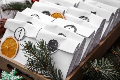 Photo of Paper bags in wooden box and festive decor on table, closeup. Christmas advent calendar