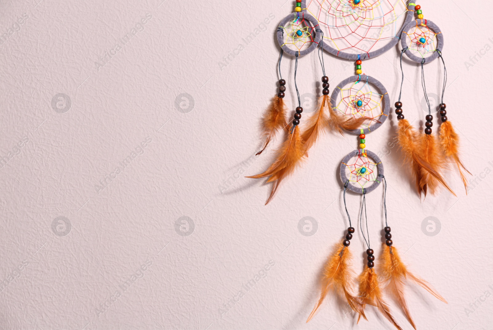 Photo of Beautiful handmade dream catcher on beige wall. Space for text