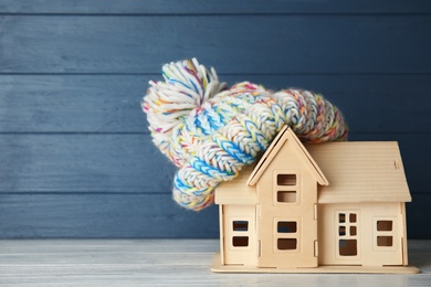 Photo of Plywood toy house with warm hat and space for text against color background. Heating system