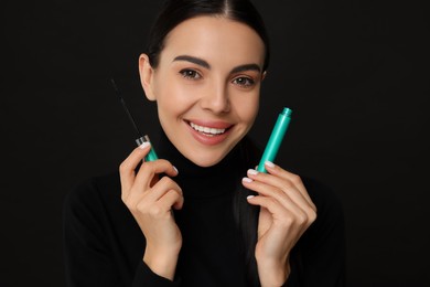 Photo of Beautiful young woman with mascara on black background