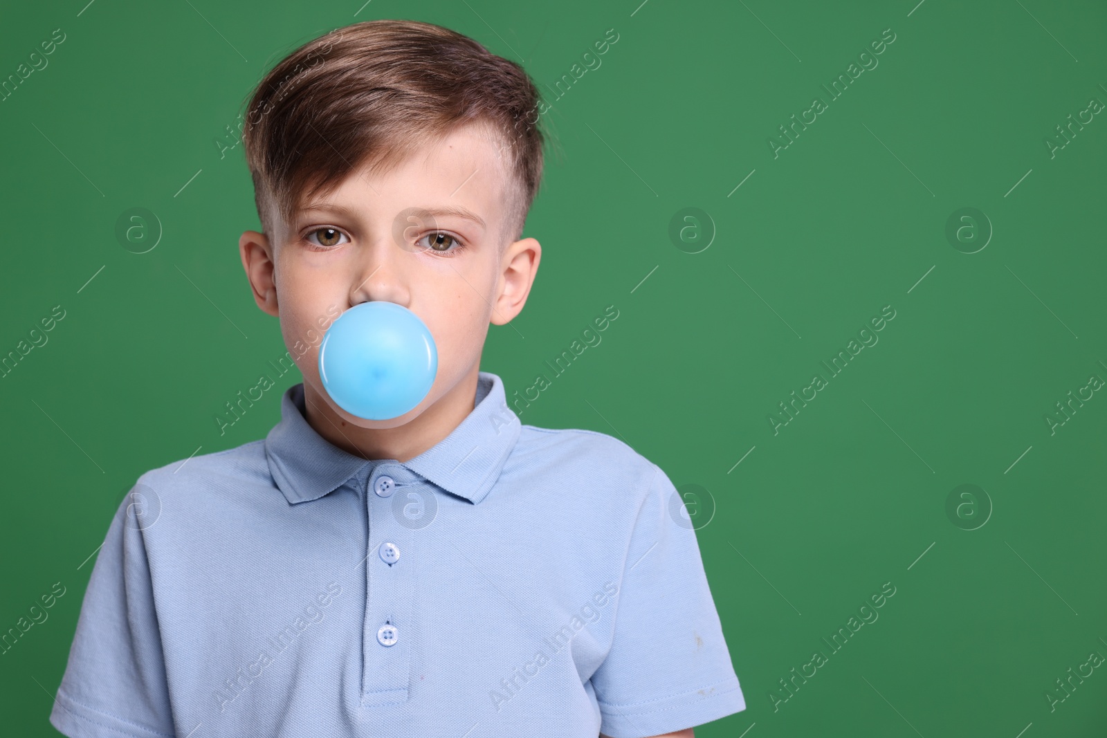 Photo of Boy blowing bubble gum on green background, space for text