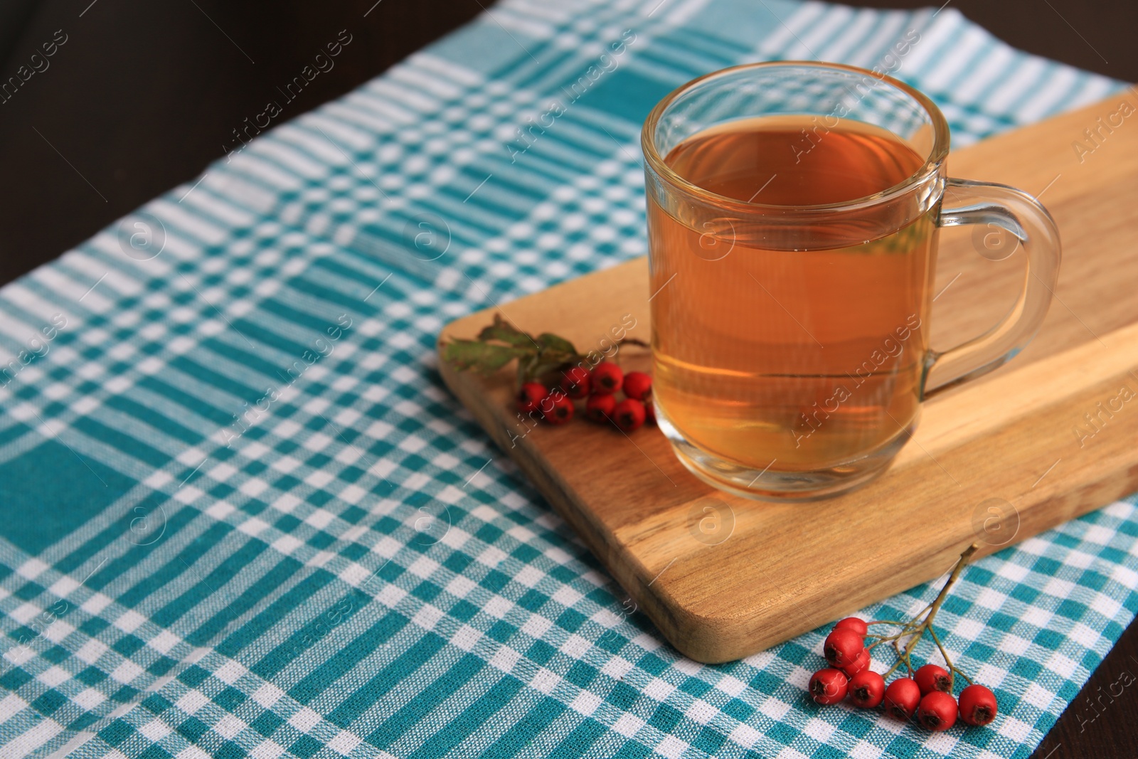 Photo of Cup with hawthorn tea and berries on table. Space for text