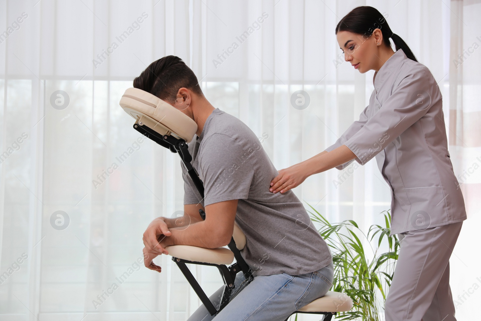 Photo of Man receiving massage in modern chair indoors