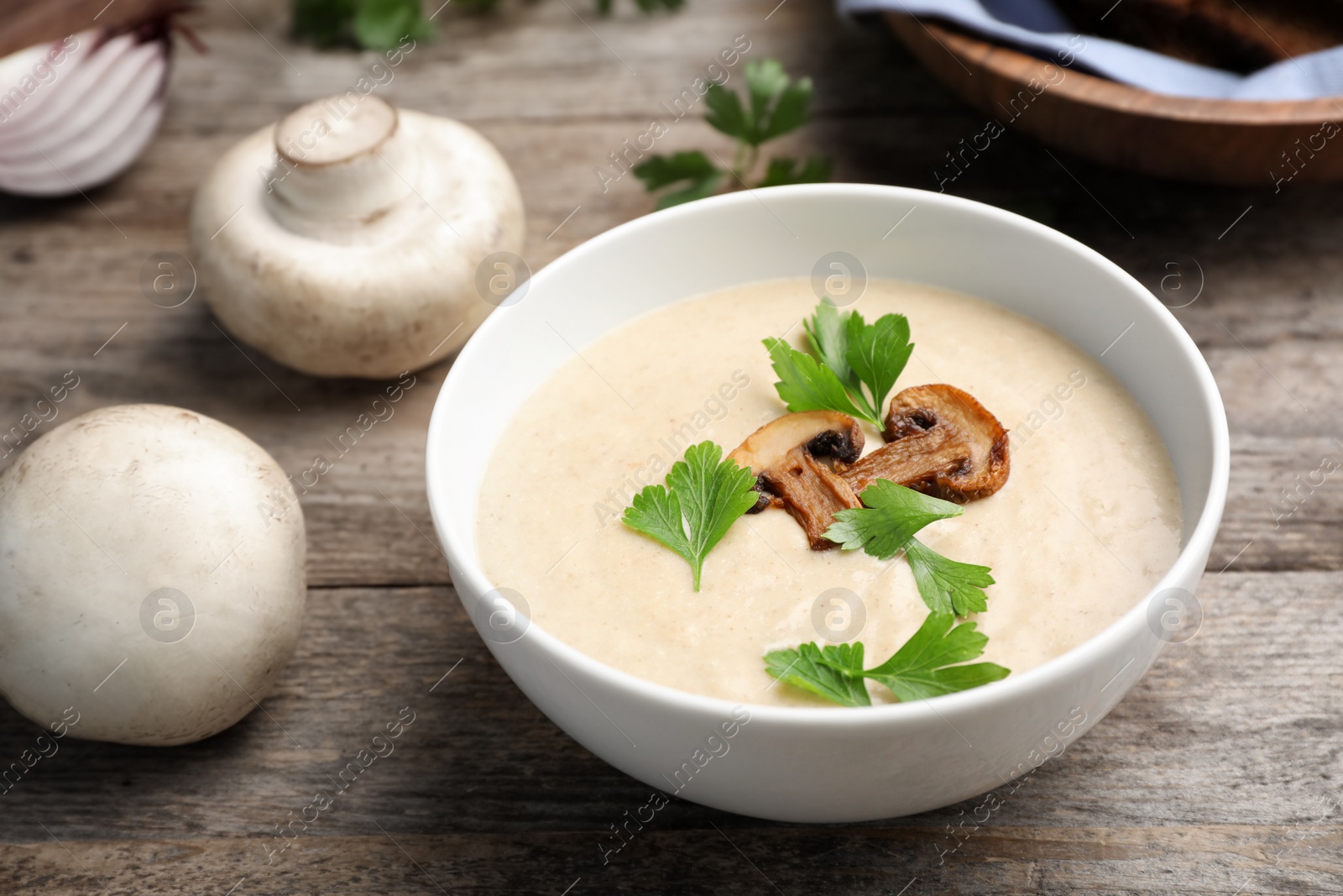 Photo of Bowl of fresh homemade mushroom soup on wooden table