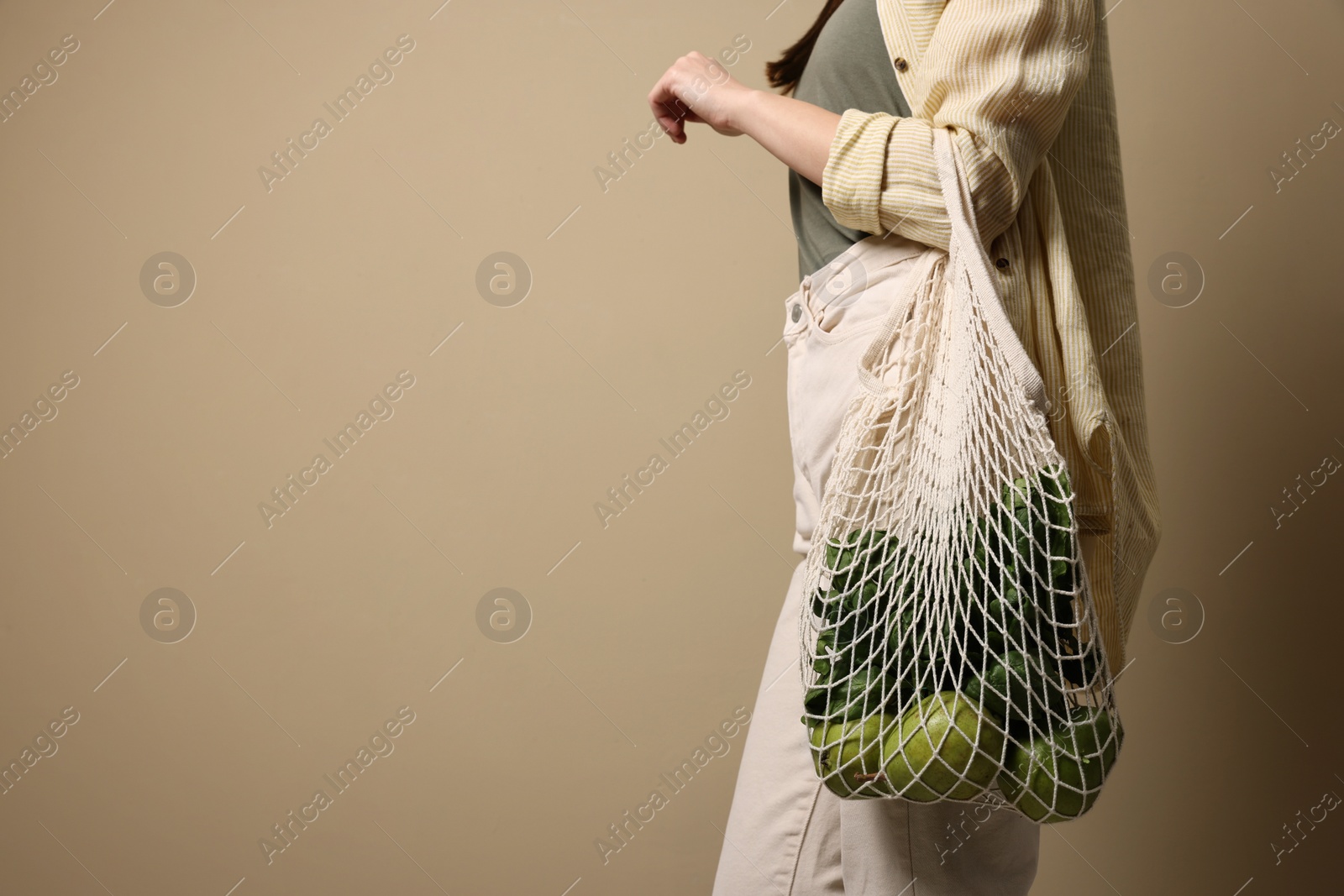 Photo of Woman with eco bag full of products on beige background, closeup. Space for text