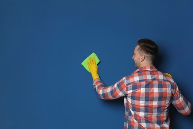 Photo of Man cleaning color wall with rag. Space for text