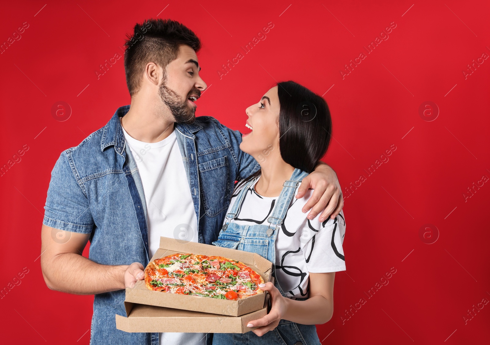 Photo of Emotional young couple with pizza on red background