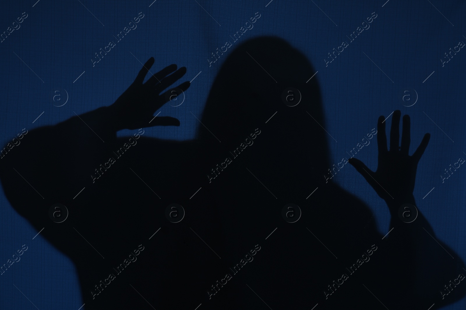 Photo of Silhouette of creepy ghost behind dark blue cloth