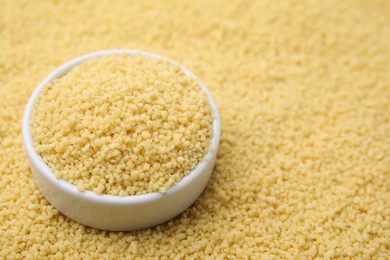 Photo of Bowl with raw couscous as background, closeup. Space for text