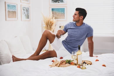 Photo of Man with glass of wine imitating picnic at home