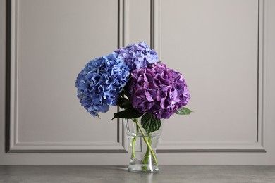 Bouquet with beautiful hortensia flowers on stone table near grey wall