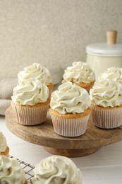 Photo of Tasty vanilla cupcakes with cream on white wooden table