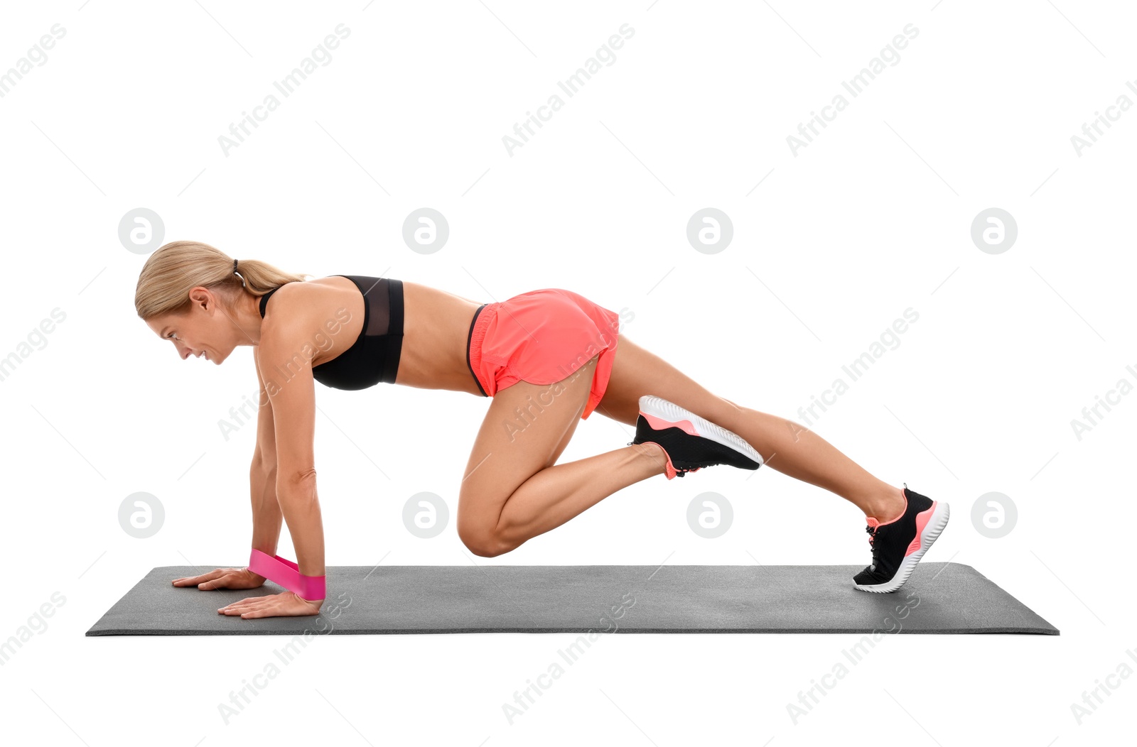 Photo of Woman exercising with elastic resistance band on fitness mat against white background