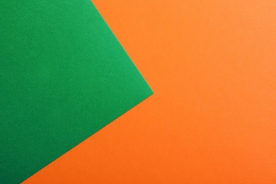 Green and orange paper sheets as colorful background, top view