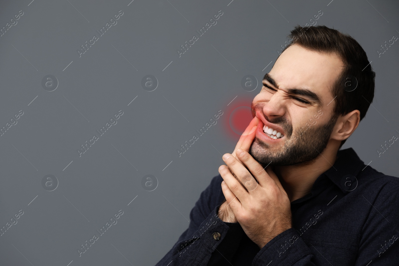 Image of Young man suffering from toothache on grey background, space for text