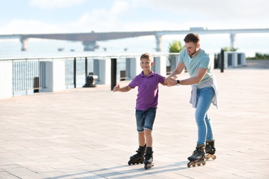 Photo of Father and son roller skating on city street