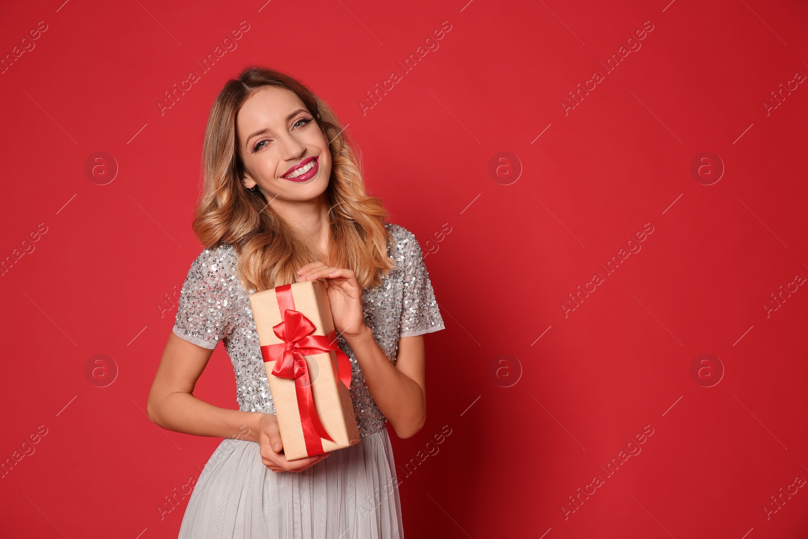 Photo of Happy woman with gift box on red background, space for text. Christmas party