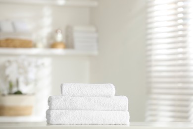 Photo of Stack of clean soft towels on white table indoors