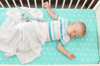 Cute little child sleeping in crib at home