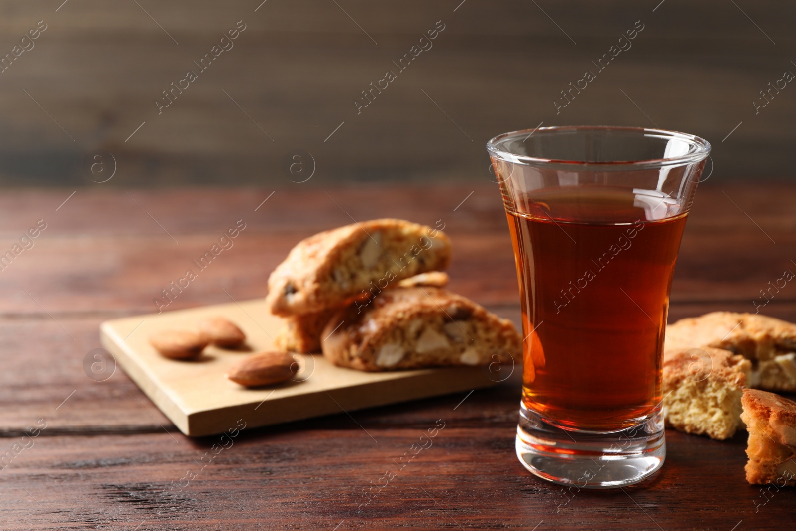 Photo of Tasty cantucci and glass of liqueur on wooden table, space for text. Traditional Italian almond biscuits