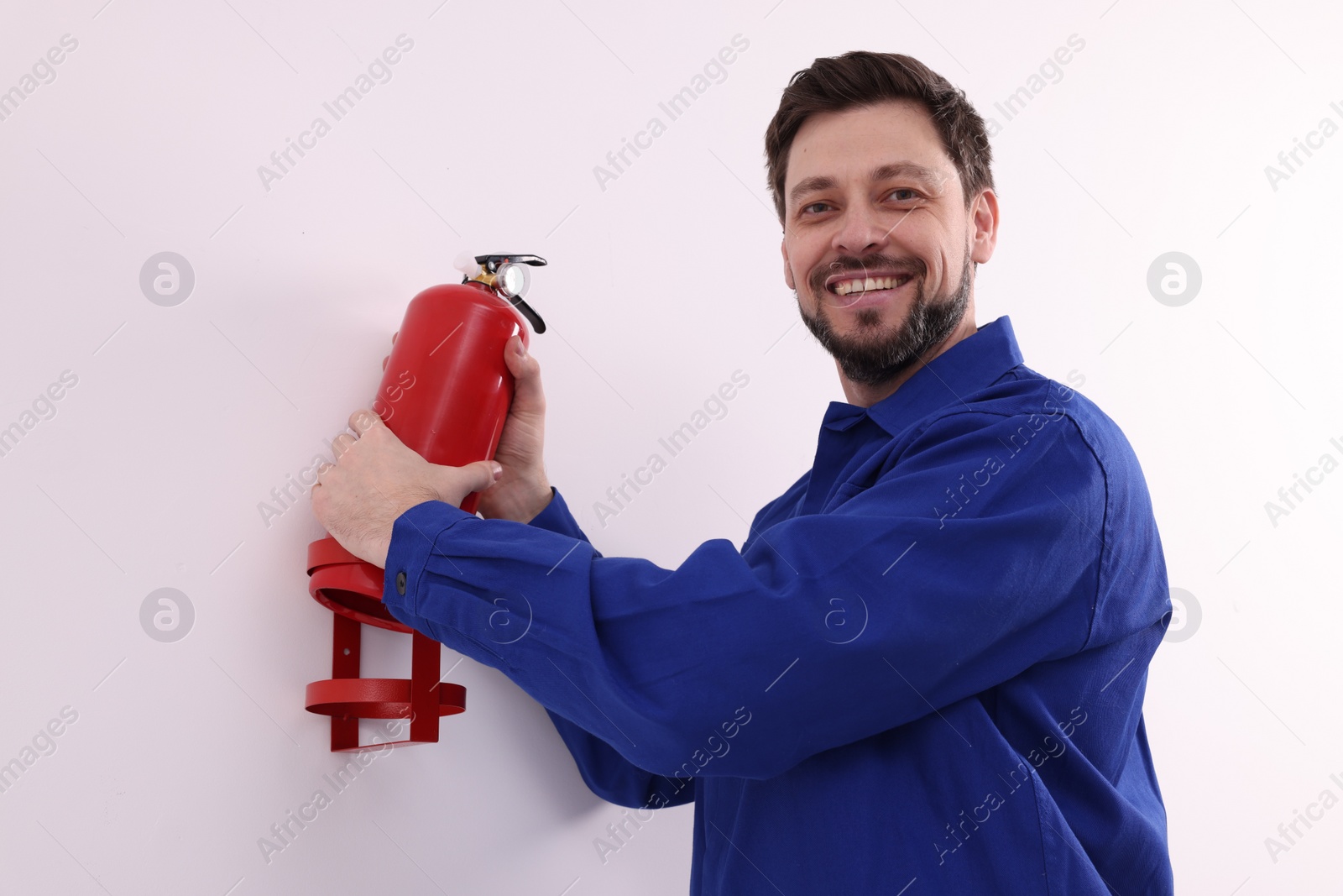 Photo of Man in uniform checking fire extinguisher indoors