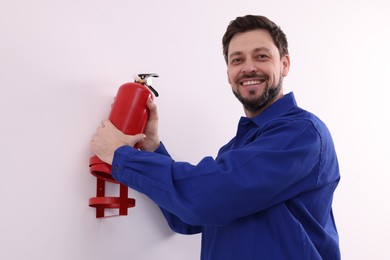Man in uniform checking fire extinguisher indoors