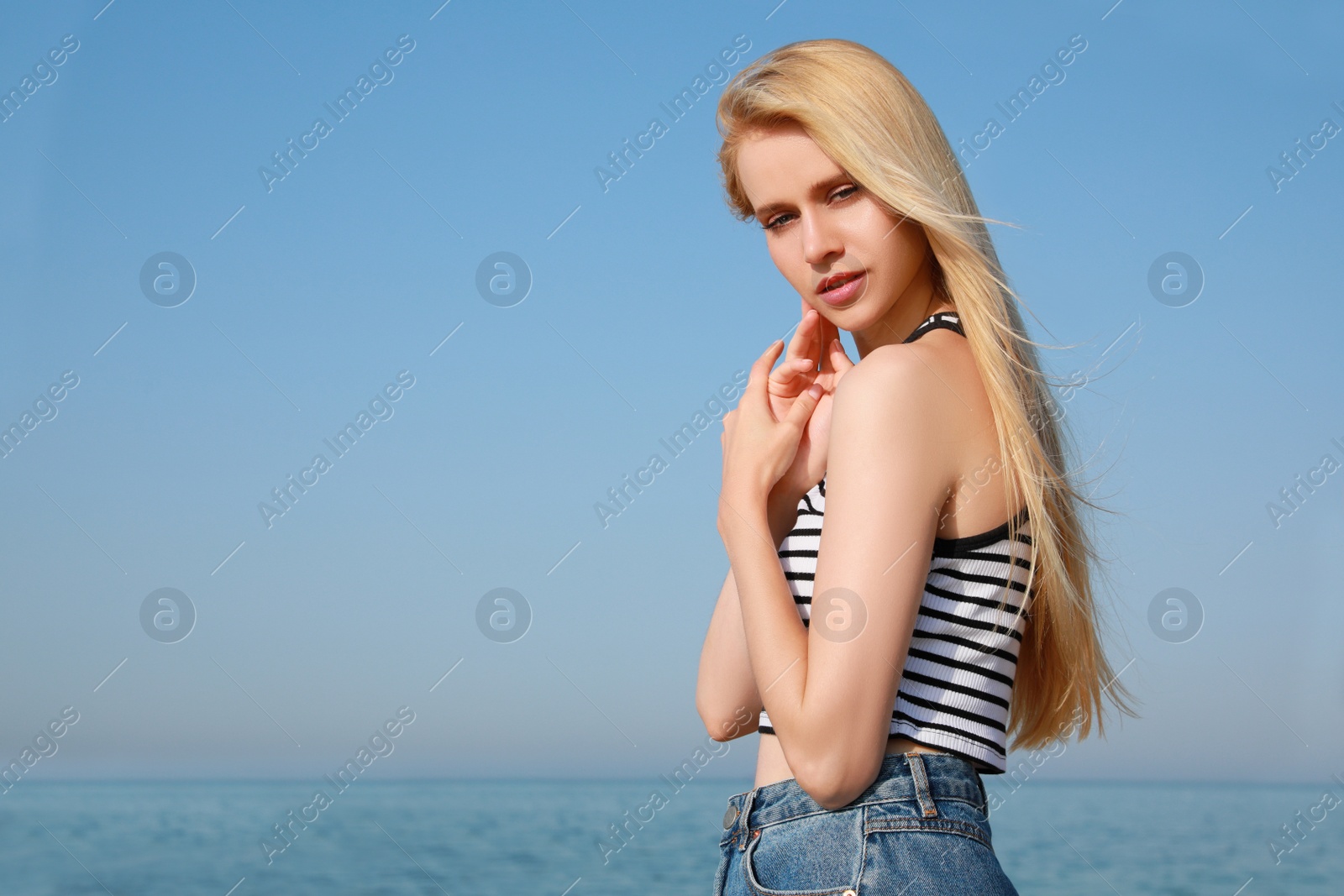 Photo of Beautiful young woman near sea on sunny day in summer, space for text