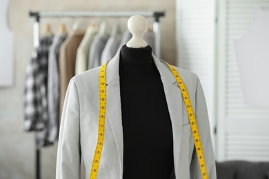 Photo of Mannequin with jacket and measuring tape in tailor shop