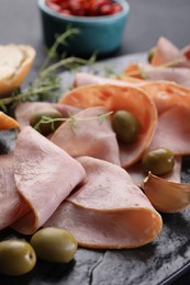 Tasty ham with olives and garlic on black board, closeup