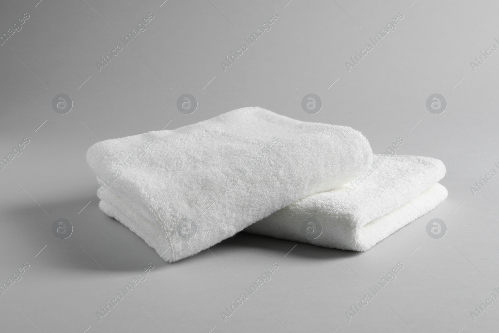 Photo of Fresh soft folded towels on light background