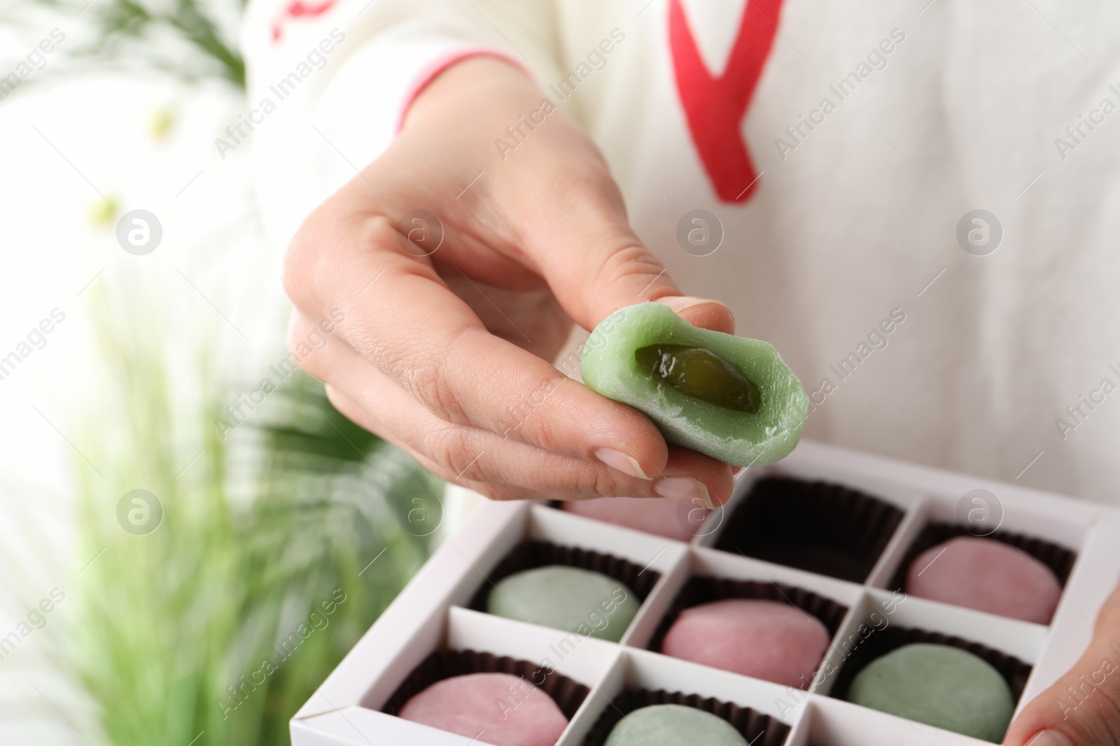 Photo of Woman holding delicious mochi above box, closeup