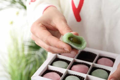 Woman holding delicious mochi above box, closeup