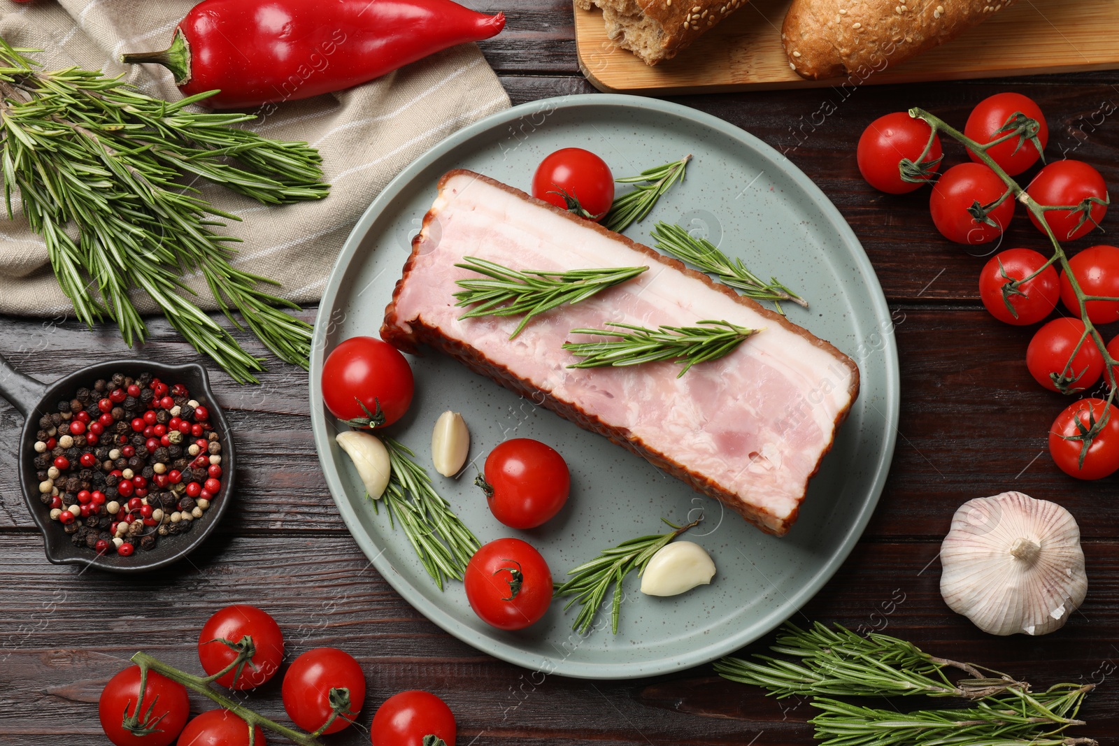 Photo of Piece of raw bacon with spices and cherry tomatoes on wooden table, flat lay