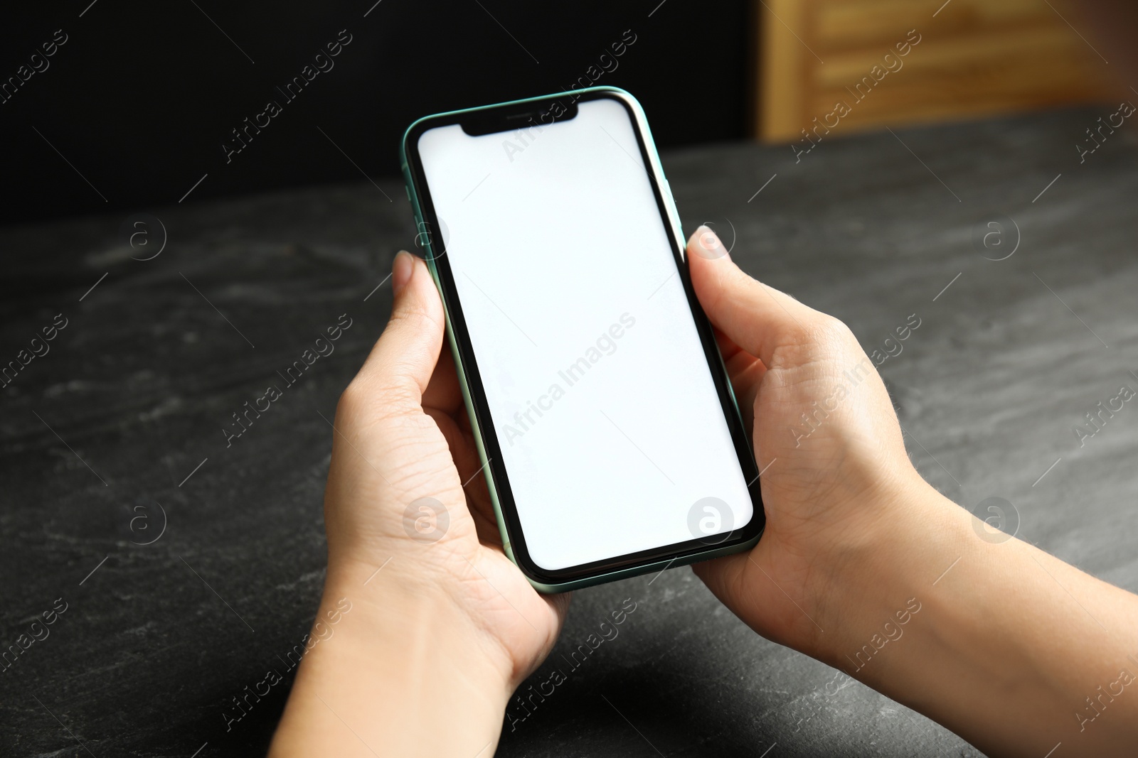 Photo of MYKOLAIV, UKRAINE - JULY 9, 2020: Woman holding Iphone 11 with blank screen at table, closeup. Space for design