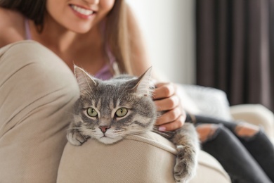 Photo of Young woman with cute cat at home, closeup. Pet and owner