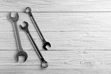 New wrenches on wooden background, top view with space for text. Plumber tools