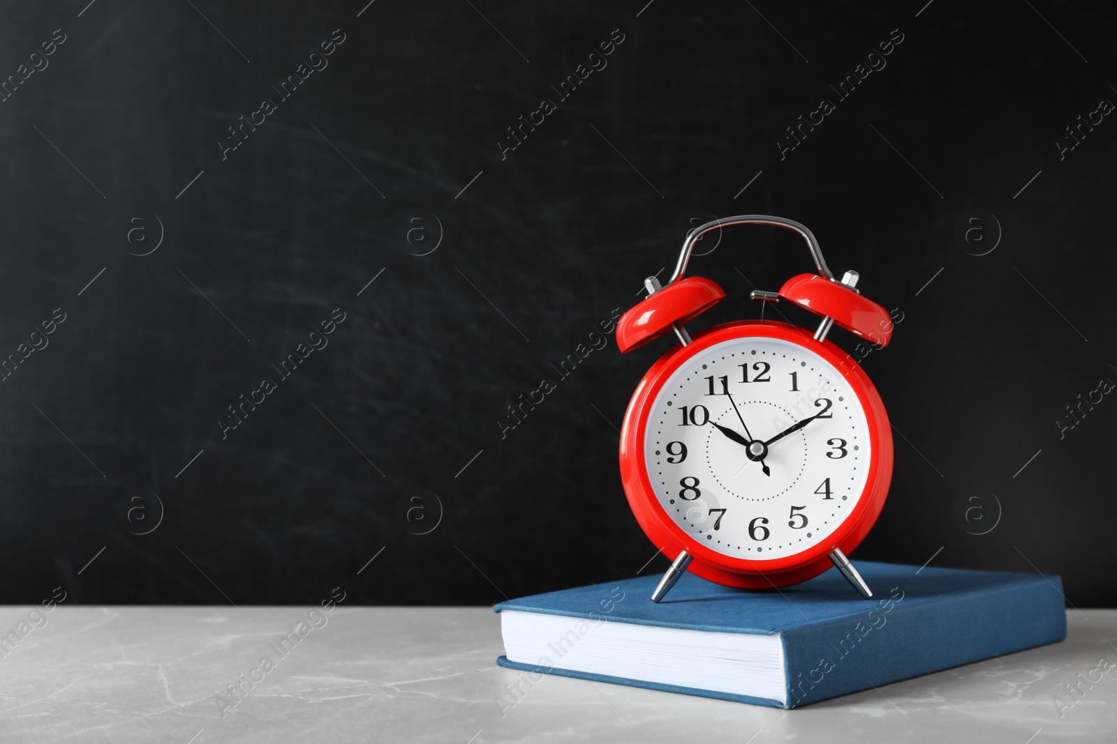 Photo of Alarm clock with book on table against color background. Time concept