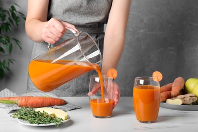 Photo of Woman pouring carrot juice from jug into glass, closeup