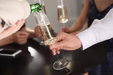 Photo of Waiter pouring champagne into man's glass at party, closeup