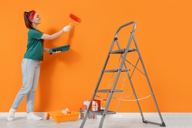 Designer painting orange wall with roller indoors
