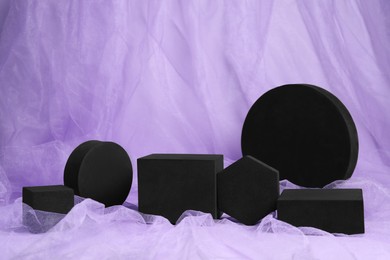 Black geometric figures on violet tulle fabric. Stylish presentation for product