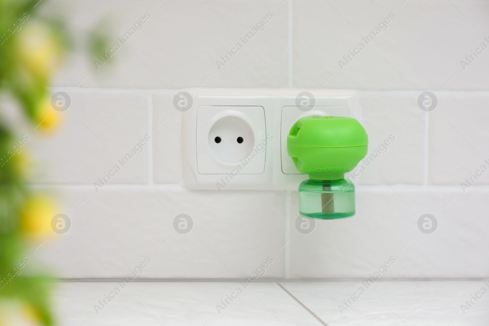 Photo of Electric vaporizer with insect repellent liquid plugged in socket at home